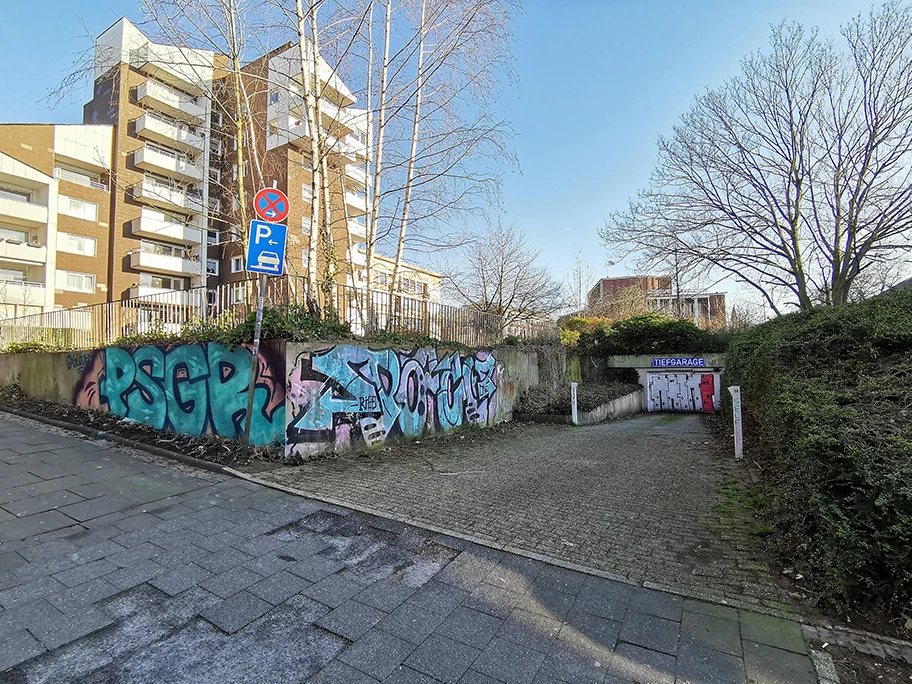 Der ehemalige Bunker Westfalenplatz in Bochum. Die Reste der Außenwände des Tiefbunkers sind links zu sehen. Rechts ist die Einfahrt zu einer Tiefgarage, die hinter dem Bunker angelegt worden ist.