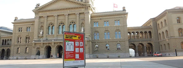 Bundeshaus Bern während COVID-19. Warntafel auf Bundesplatz, Polizeiauto und Sperrgitter Richtung Bundesterrasse.