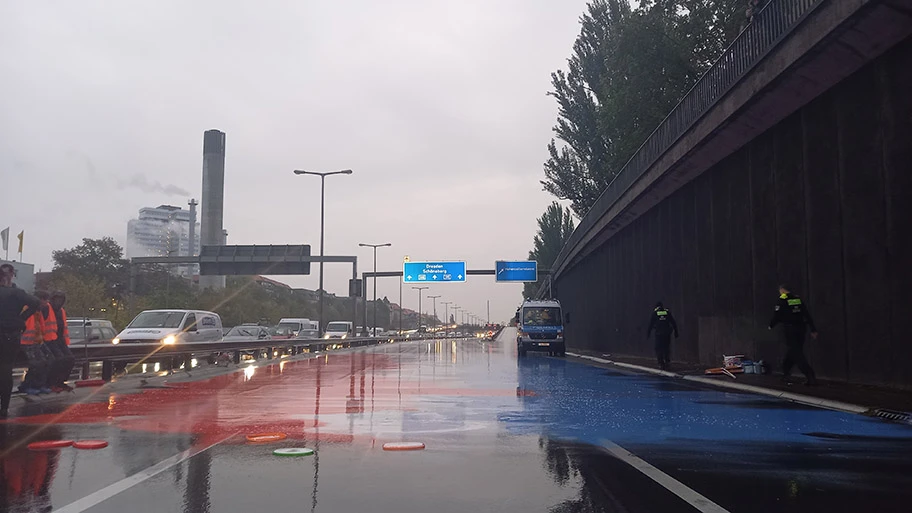 Unterstützer:innen der Letzten Generation malen die Niederländische Flagge auf die A100.