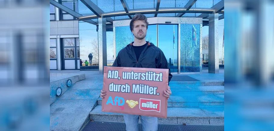 Ein Unterstützer der Neuen Generation vor dem AfD-blauen Firmensitz von Müllermilch in Aretsried, 4. März 2025.