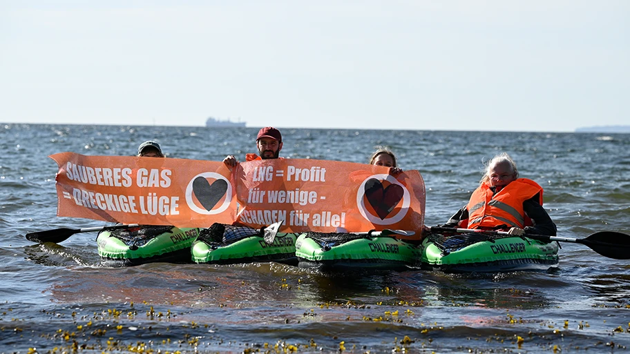 Unterstützer:innen der Letzten Generation vor dem Rügener LNG-Terminal (im Hintergrund).